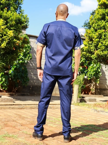 Back view of a man wearing a navy blue short-sleeve shirt and trouser set with traditional patterned cuff details.